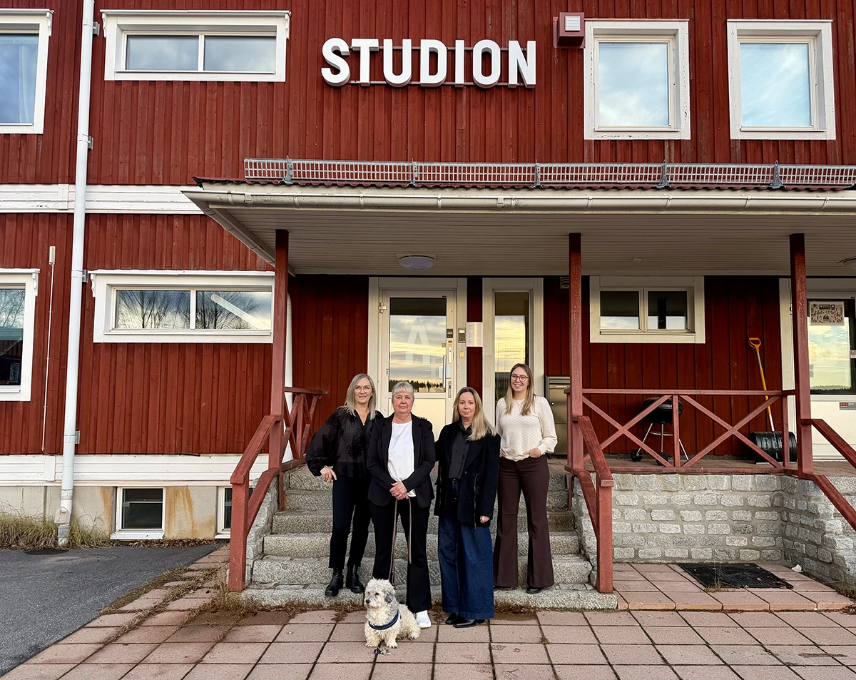Fyra medarbetare från Bokföringsbyrån står framför entrén till Studion i Boden, där företagets nya kontor finns. Framför gruppen sitter en liten vit hund.
